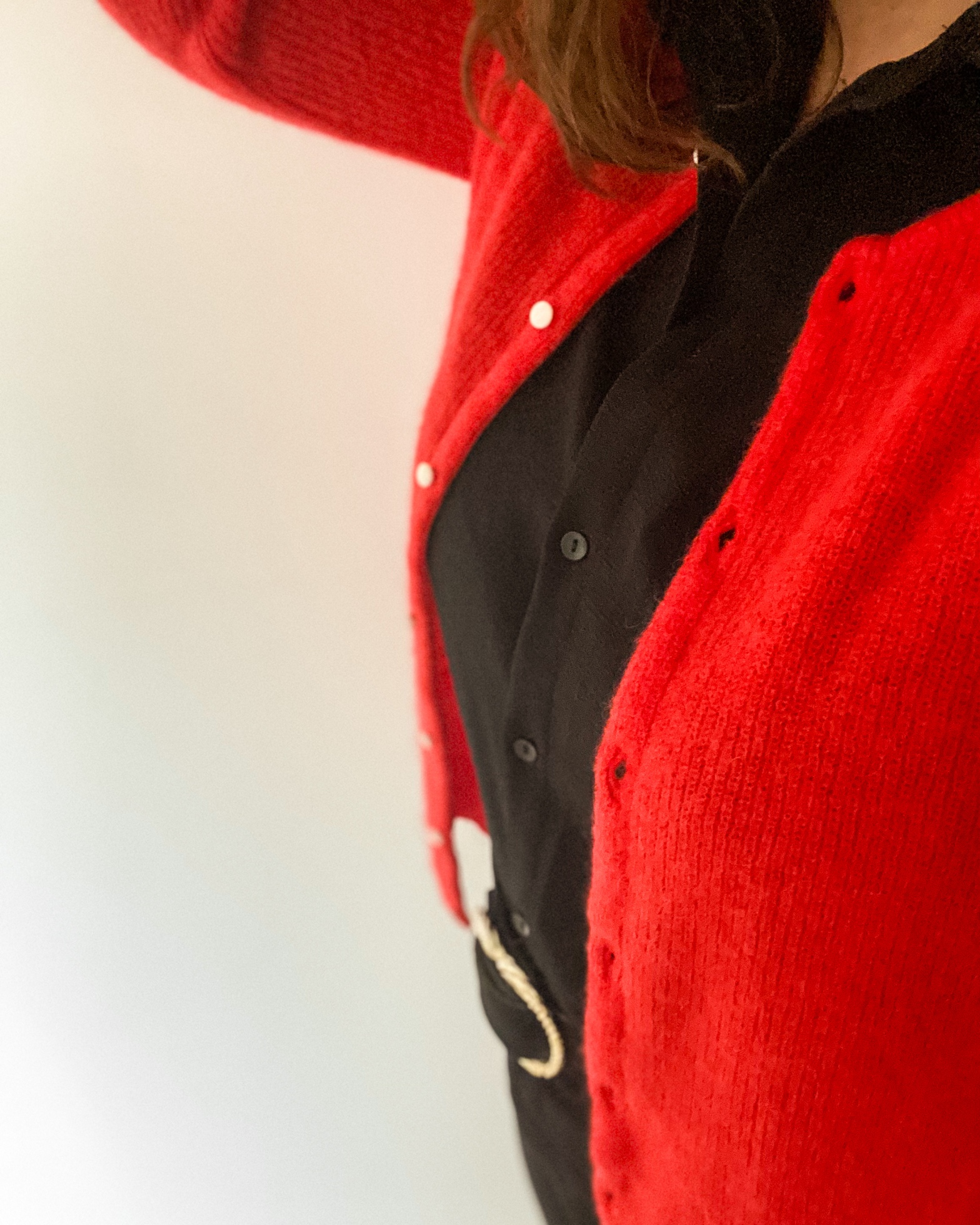 Buste de femme, gilet en laine rouge sur une chemise noire
